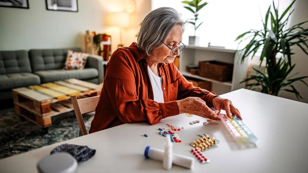 An older woman sorts pills into boxes