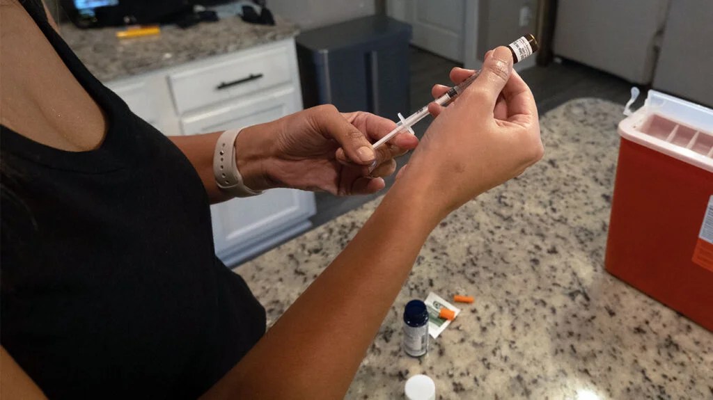 A person filling up an injection with fluid from a vial, depicting GLP-1 agonists like Ozempic