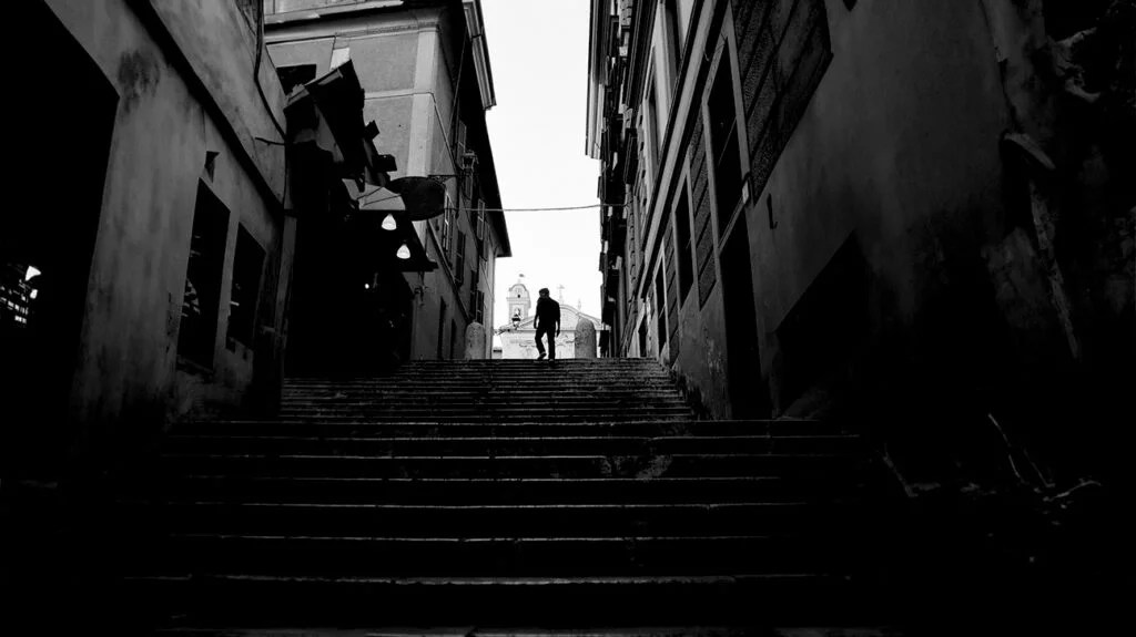 A view of a narrow street with a man at the top of a staircase